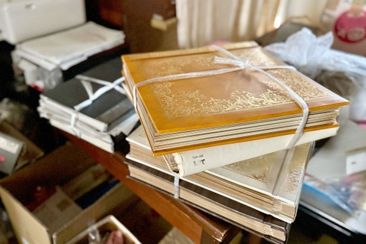 紐で縛られた古いアルバムと、片付けられずに残された乱雑な部屋。親の断捨離や生前整理を象徴するイメージ。