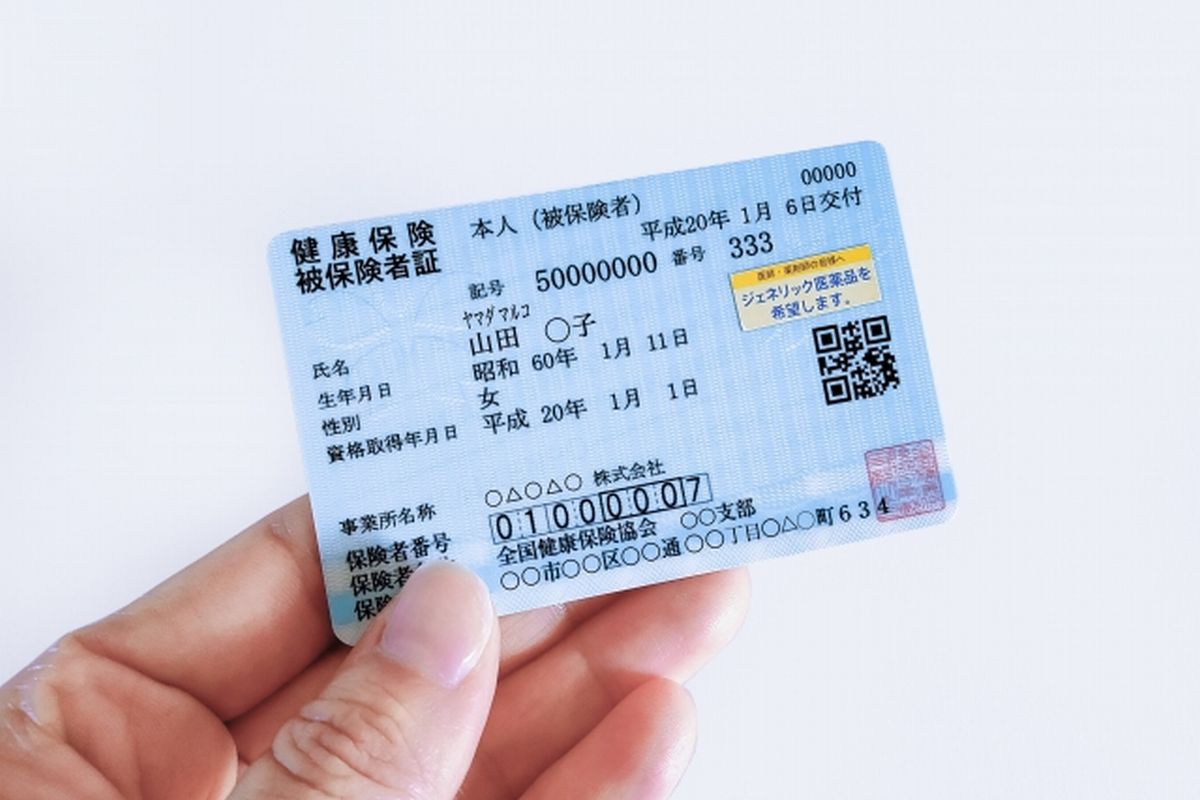 女性の手に持たれた健康保険被保険者証の見本（クローズアップ）。高齢者の医療費控除のイメージ