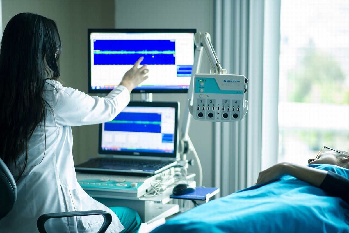 高齢者が病院のベッドで医療機器を使い、女医から診断を受けている様子