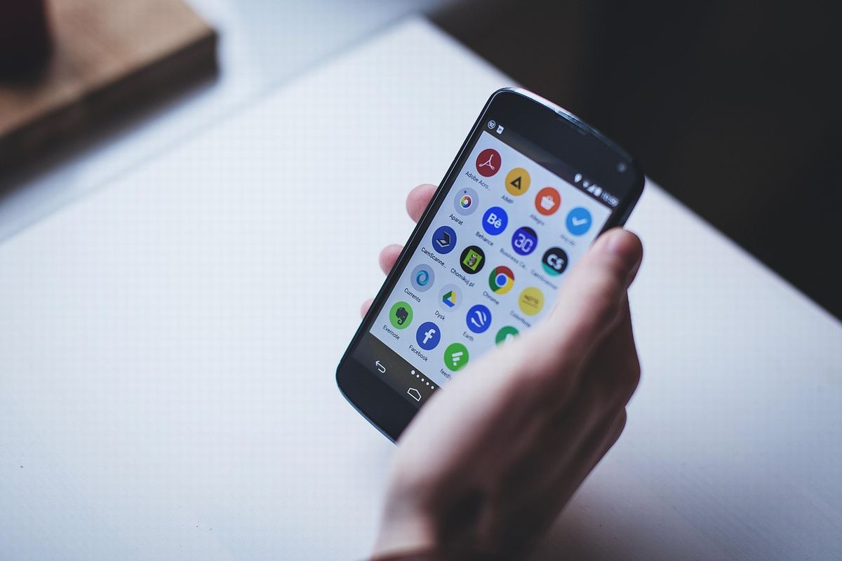 机の上で右手にスマホを持つ高齢者の手元
